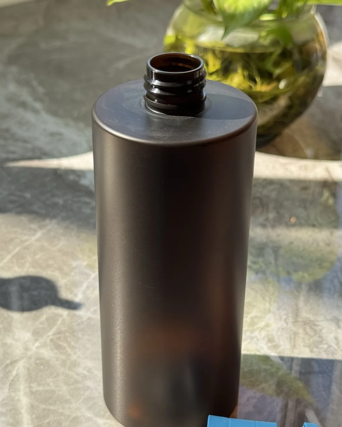 Amber-brown HDPE bottle with a screw neck for home care, with a blue trigger pump beside it